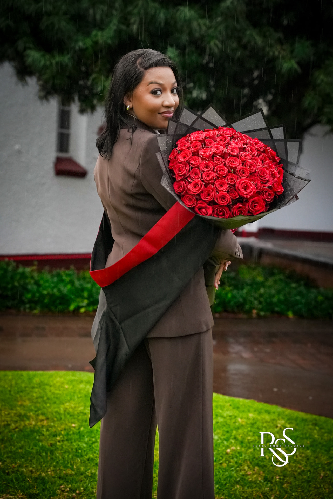 Graduate holding red roses in the rain